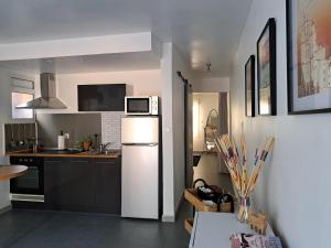 eine Küche mit einem weißen Kühlschrank und einer Mikrowelle in der Unterkunft Appart Béziers - Campagne de Montimas in Béziers