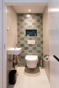 a bathroom with a toilet and a sink at Lovina Beach House by Urban Home Stay in Egmond aan Zee +19 photos