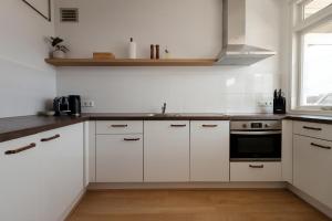 a kitchen with white cabinets and a sink at Lovina Beach House by Urban Home Stay in Egmond aan Zee