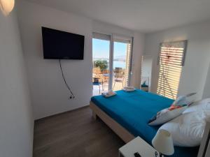 a bedroom with a bed and a flat screen tv at Blauer Horizont in Povljana