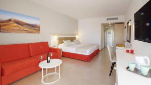 a living room with a red couch and a bed at Hotel Lanzarote Village in Puerto del Carmen