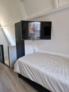 ein Schlafzimmer mit einem Bett und einem Flachbildfernseher an der Wand in der Unterkunft Bed & Breakfast De Punt in Monnickendam