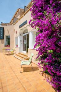 un bâtiment avec des fleurs violettes et une chaise sur une terrasse dans l'établissement Bel Ombra Hôtel, à Bandol