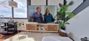 a living room with a tv with a man and a woman at Sally's Loft - Penthouse - Honeymoon suite in Ponta do Sol +10 photos