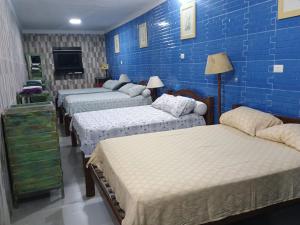 a room with four beds against a blue brick wall at Hostel e pousada paz e benção in Mossoró