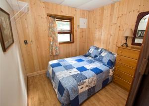 a bedroom with a blue and white bed and a window at The Pines Cottage Resort in Oxtongue Lake
