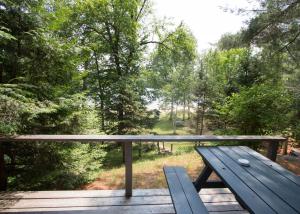 un banc en bois installé au-dessus d'une terrasse en bois dans l'établissement The Pines Cottage Resort, à Oxtongue Lake