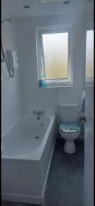 ラーグスにあるLargs Top Floor Flatの浴槽、トイレ、窓のあるバスルーム +2枚の写真