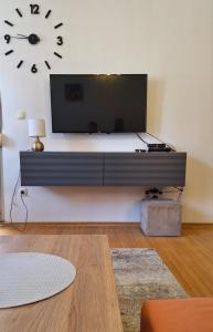 a living room with a tv and a clock on the wall at Morina Apartment Prishtina in Pristina
