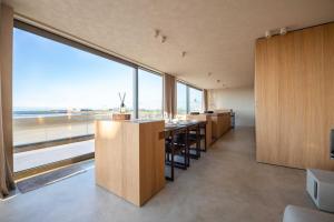 a dining room with a long table and large windows at Beach House Stellar in Zeebrugge