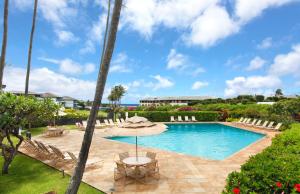 a swimming pool with an umbrella and chairs at 2 bedrooms Condo few mins walk to Beaches & Pool in Koloa