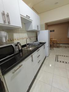 a kitchen with white cabinets and a sink and a microwave at résidence sara in Fez