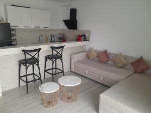 a living room with a couch and two bar stools at Luxueux appartement meublé bien équipé avec accès piscine et salle de sport in Nabeul