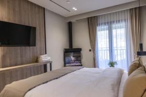 a bedroom with a bed and a flat screen tv at Polyzos Luxury Suites Meteora #4 - Adults Friendly in Kalabaka