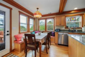 eine Küche mit einem Tisch, Stühlen und Fenstern in der Unterkunft 3br Hot Tub Ocean Views & King Beds Near Beach in Nehalem