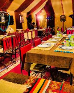 a dining room with a long table and red chairs at Camp luxury Merzouga in Merzouga