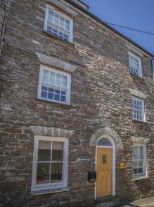 a brick building with a wooden door and windows at Stone's throw Cottage Mevagissey in Mevagissey