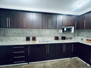 a kitchen with dark brown cabinets and a sink at Casa Amplia in Ambato +8 photos