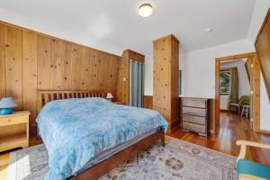 a bedroom with a bed and a wooden wall at Cottage By The Sea Nedonna Beach Getaway in Rockaway Beach