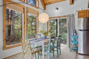 a dining room with a table and chairs and windows at Charming Beach Cabin Close Beach Access in Rockaway Beach