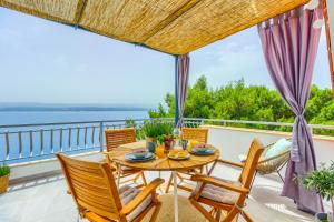 a table and chairs on a balcony with a view of the water at Beach Apartment Stanici in Stanići