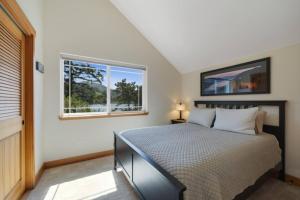 ein Schlafzimmer mit einem Bett und einem Fenster in der Unterkunft Lakefront Retreat Hot Tub & Semi-private Dock in Rockaway Beach