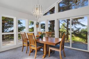 jadalnia z drewnianym stołem, krzesłami i oknami w obiekcie Cape Meares 4br Oceanview Retreat King Bed w mieście Tillamook