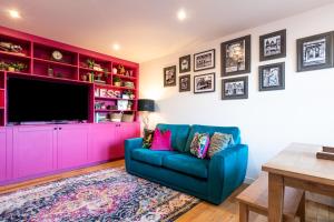 a living room with a blue couch and a pink cabinet at Ness in the City in Inverness