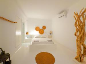 una stanza bianca con un letto e un albero dentro di Villa Secret 55 Mykonos a Fanari