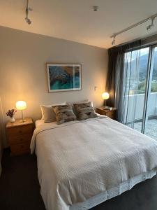 a bedroom with a large bed and a large window at The Bowenview Bothy in Queenstown