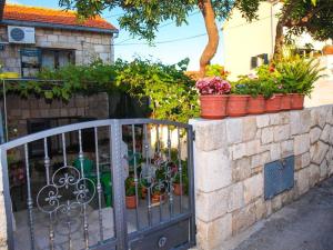 a stone wall with potted plants on top of a gate at Apartment Simi in Postira