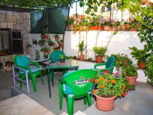 a patio with green chairs and a table and flowers at Apartment Simi in Postira +11 photos
