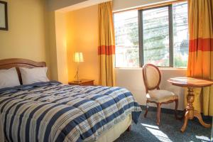 ein Schlafzimmer mit einem Bett, einem Stuhl und einem Fenster in der Unterkunft Hotel Sucali in Huaraz