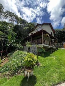 a house with a porch and a potted plant in the yard at Bangalô império verde in Chã Grande