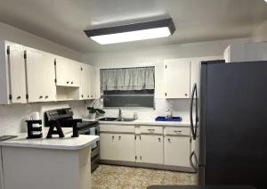 a kitchen with white cabinets and a black refrigerator at Private Suite inside SHARED home - Vida Room in Miami