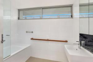 a white bathroom with a sink and a shower at Hume Parade 19, Unit 2, Currimundi in Kawana Waters