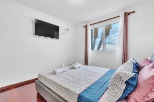 ein Schlafzimmer mit einem Bett und einem Fernseher an der Wand in der Unterkunft Cozy Seaside Cottage Ocean Views and Near Beach in Caniço