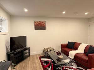a living room with a red couch and a tv at Calm & Cozy Private Suite in Surrey