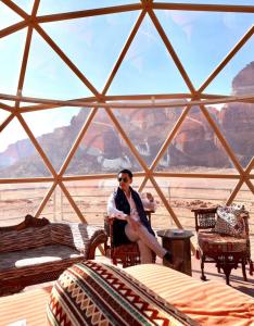 a woman sitting in a room with a view of the grand canyon at Rum warm bubble camp in Wadi Rum