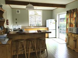 a kitchen with a counter with stools and a refrigerator at Peace, privacy and proximity in Hanmer Springs