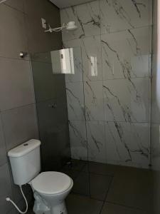 a bathroom with a white toilet and marble walls at Residencial Mangueiral in Paracatu