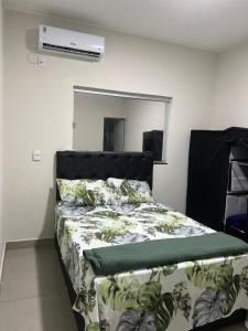a bedroom with a bed with a green comforter at Residencial Mangueiral in Paracatu