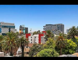 Un horizonte de ciudad con palmeras y edificios en Chic Hollywood Retreat 2Bed Rooftop Pool with Iconic Views, en Los Ángeles
