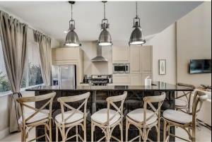 Una cocina con un mostrador con sillas alrededor. en Magic Village Townhouse, Minutes from Disney, Pool, Grill, en Abbeyville