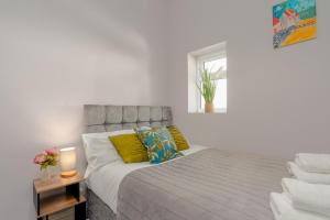a bedroom with a bed with yellow pillows and a window at Richmond Terrace - Cosy and Modern Stay in Darwen