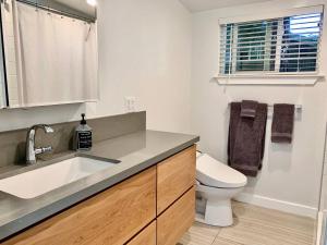 a white bathroom with a sink and a toilet at King Bed-Peaceful Modern Cottage-Garden Setting in Carmichael