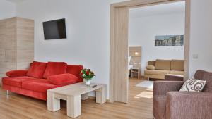ein Wohnzimmer mit einem roten Sofa und einem Tisch in der Unterkunft Das Falk Apartmenthaus in Nürnberg