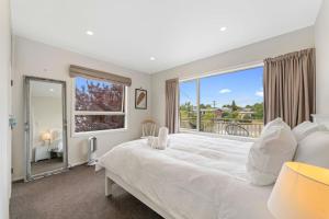 a bedroom with a large white bed and a large window at First floor apartment in Taupo