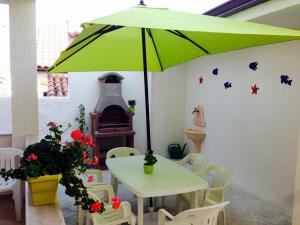 Case Playa في باليستراتي: مظلة خضراء في غرفة مع طاولة وكراسي