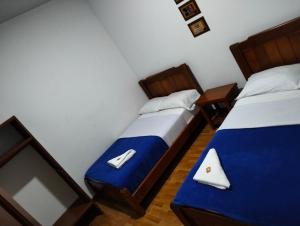 two beds in a room with blue and white sheets at Hotel café Arábico in Líbano